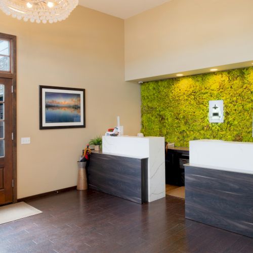 A modern living room with a green accent wall, a white couch, a small black table, a bright yellow wall-art, and a wooden door.